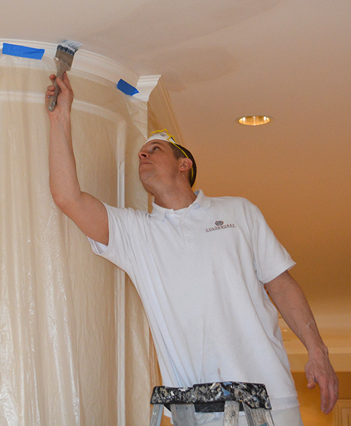 Man on ladder painting ceiling